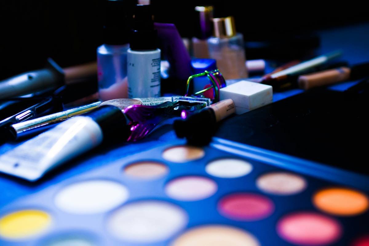 Assortment of colorful makeup palettes arranged on a vanity with brushes and sponges